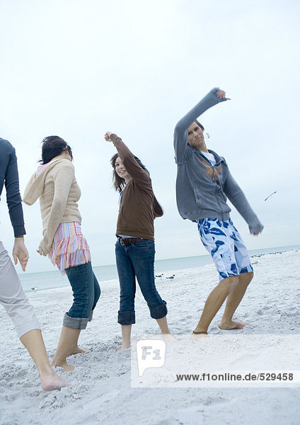 Junge erwachsene Freunde tanzen am Strand