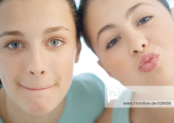 Zwei Mädchen im Alter von 15 Jahren  eine verzieht sich  die andere schürzt die Lippen.