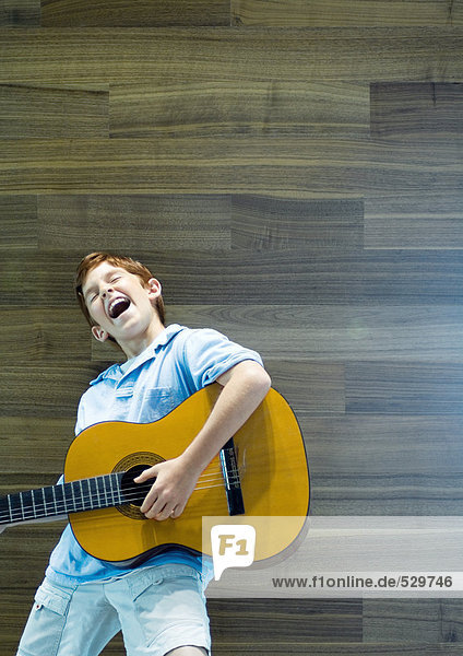 Junge spielt Gitarre und singt mit Emotionen