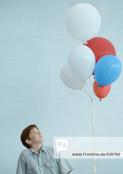 Junge schaut auf einen Haufen Ballons.