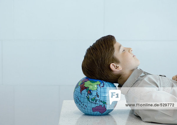 Junge ruht Kopf auf Globus