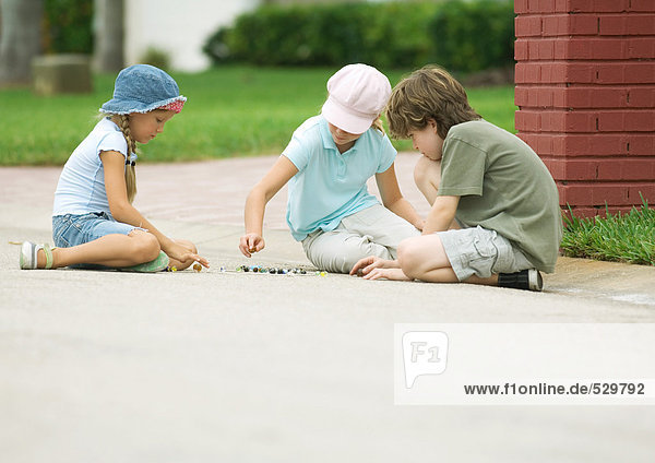 Children playing marbles in street