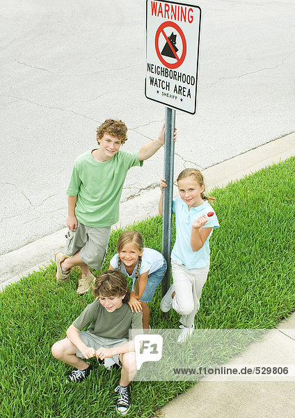 Suburban children grouped around neighborhood watch sign