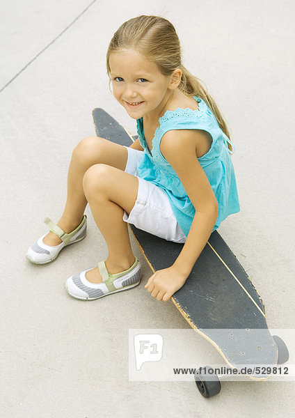 Mädchen auf Skateboard sitzend