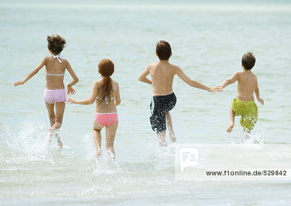 Children running in surf at beach