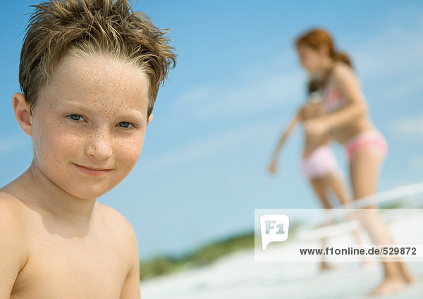 Junge lächelnd  Kinder spielen im Hintergrund  am Strand