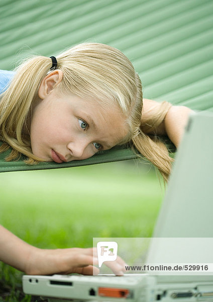 Mädchen in Hängematte liegend mit Laptop