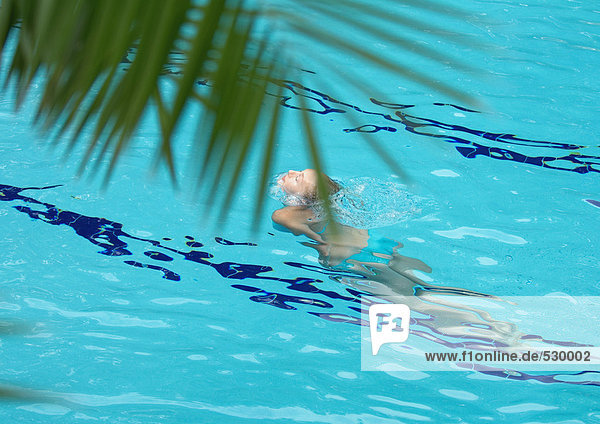 Frau hebt Kopf aus dem Wasser in den Pool