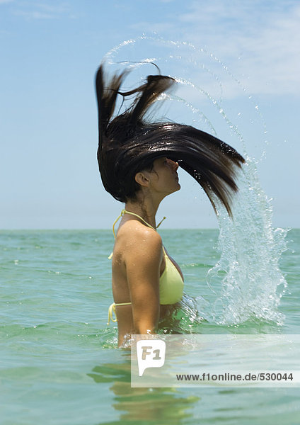 Frau im Meer stehend Haare werfend