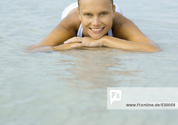 Frau im flachen Wasser am Strand liegend