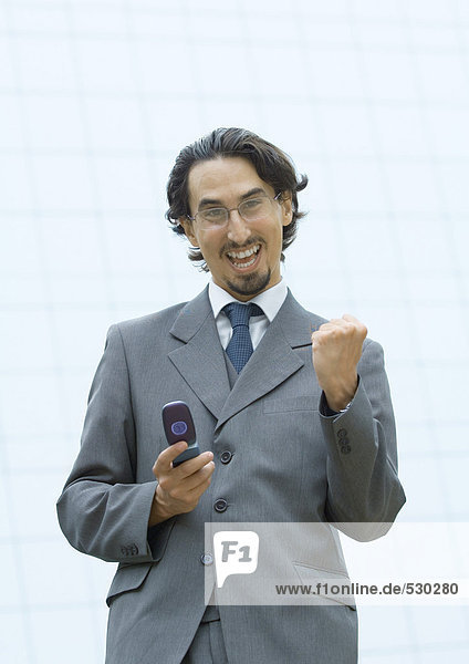 Businessman holding cell phone  making fist and shouting