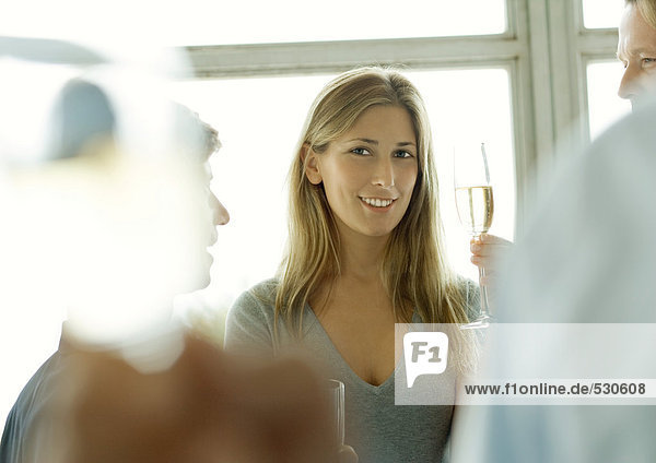 Junge Frau hält während der Betriebsfeier ein Glas Champagner hoch