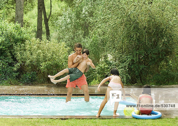 Father playing with children in swimming pool