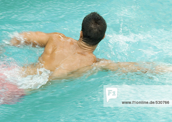 Man swimming in pool  rear view