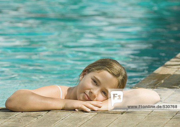 Little girl in swimming pool  resting head on edge