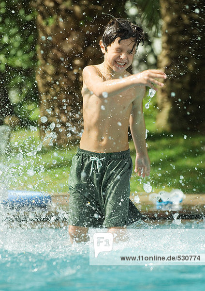 Boy standing in swimming pool  splashing