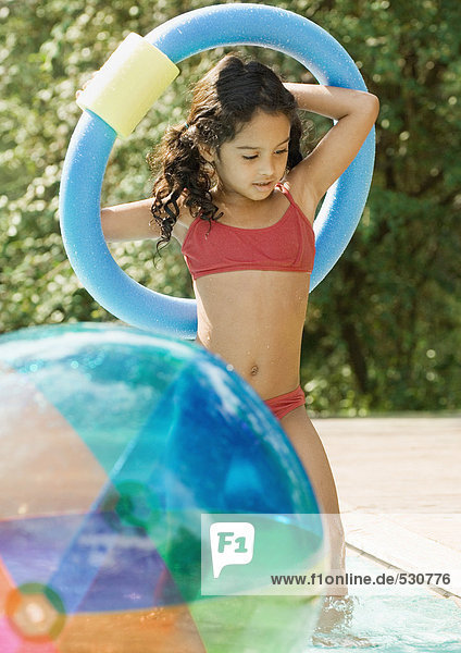 Girl in swimming pool  holding ring over head