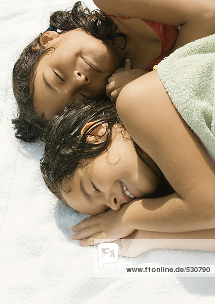 Two girls lying down together  one wrapped in towel