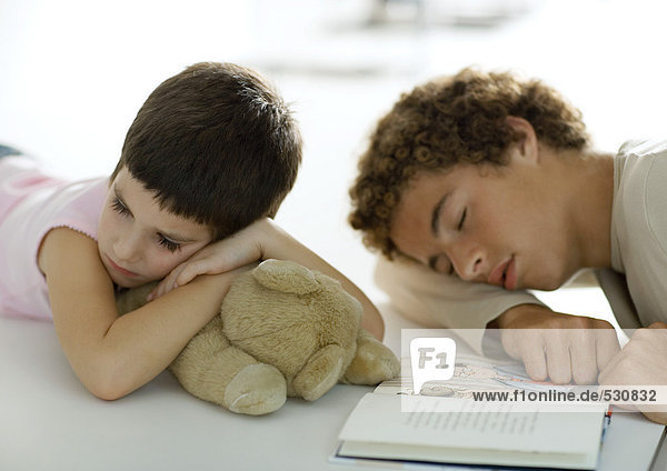 Jugendlicher Junge und jüngere Geschwister  die beim Lesen des Buches einschlafen.