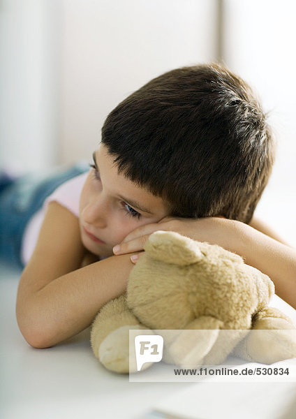 Kind ruht Kopf auf Teddybär