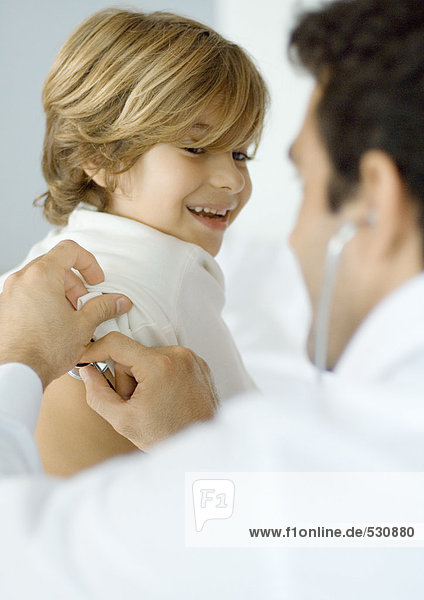 Mann untersucht Junge mit Stethoskop