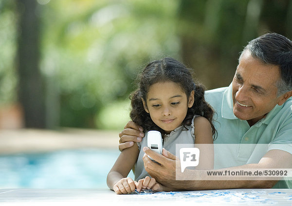 Mature man showing granddaughter cell phone
