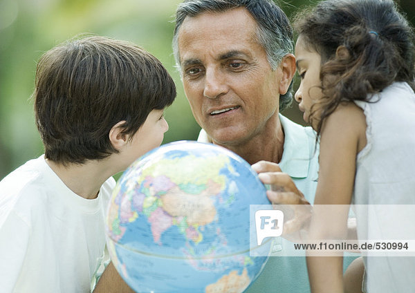 Erwachsener Mann mit Enkelkindern auf dem Globus