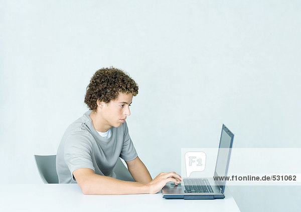 Junger Mann mit Laptop am Tisch