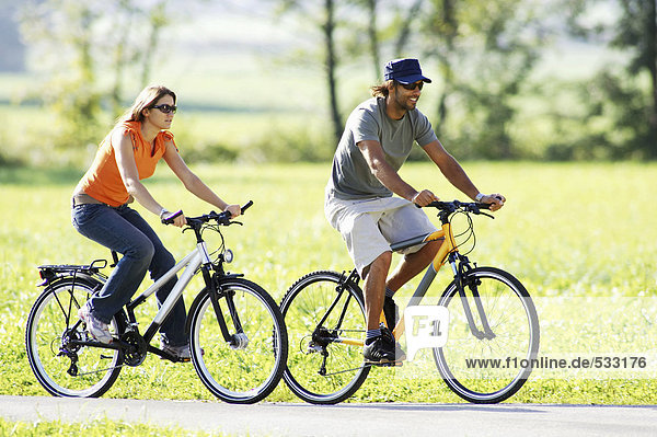 Germany  Bavaria  couple riding bicycle  side view