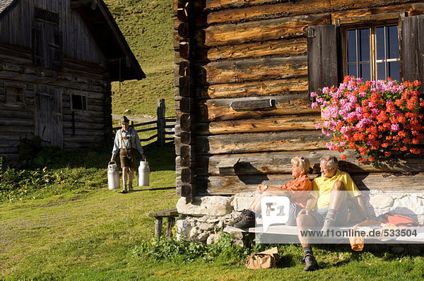 Ehepaar vor der Almhütte sitzend  Bauer mit Milchkanne