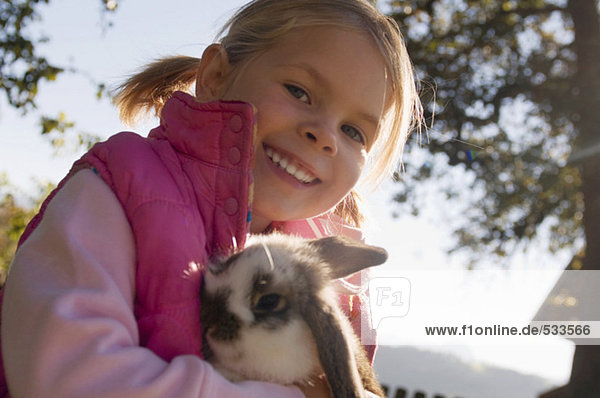 Mädchen (4-5) hält Kaninchen  Portrait