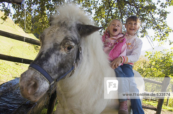 Zwei Mädchen auf Pony sitzend