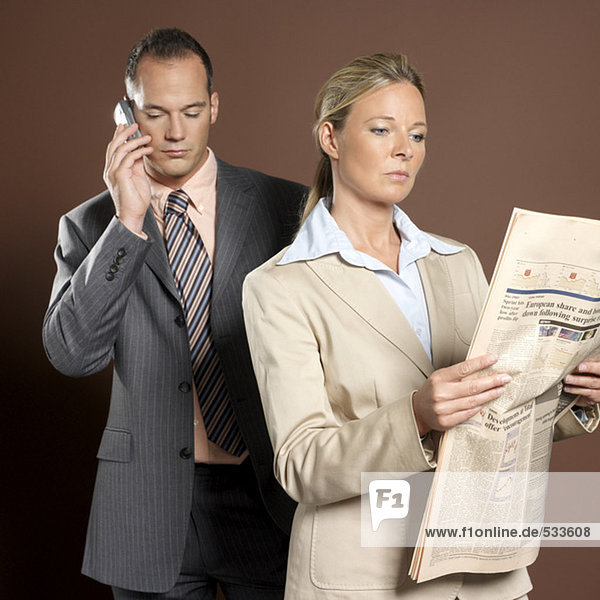 Geschäftsmann und Geschäftsfrau Mann mit Handy,  Frau mit Zeitung