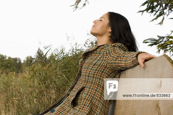 Young woman sitting on bench  eyes closed