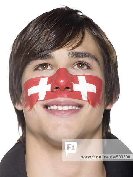 Junger Mann mit Schweizer Fahne auf Gesicht gemalt