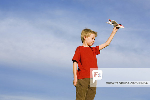 Boy (10-12) holding model aircraft