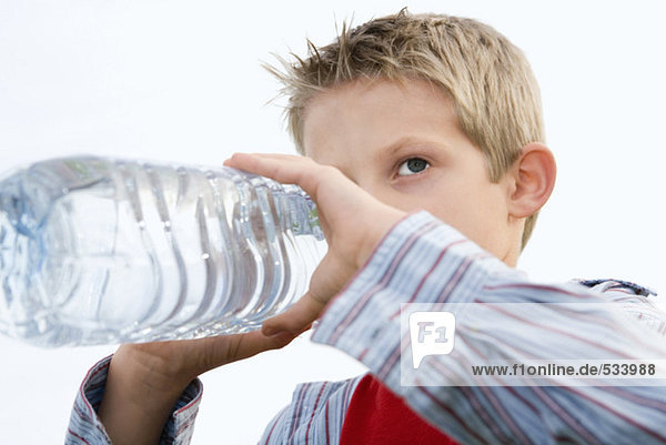 Junge (10-12) trinkt aus der Wasserflasche