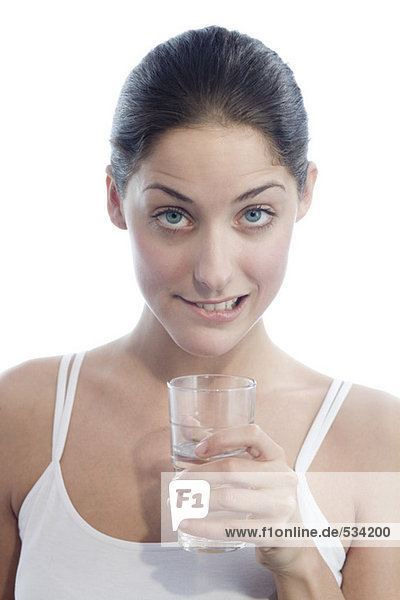 Young woman holding glass of water  biting lip  portrait  close-up