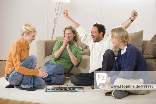 Family playing board game  man with arms outstretched  smiling