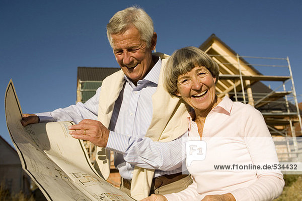 Senior-Paar-Halteplan vor dem teilweise gebauten Haus
