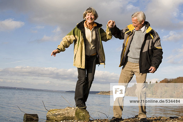 Senior couple by sea  woman standing on wood  smiling