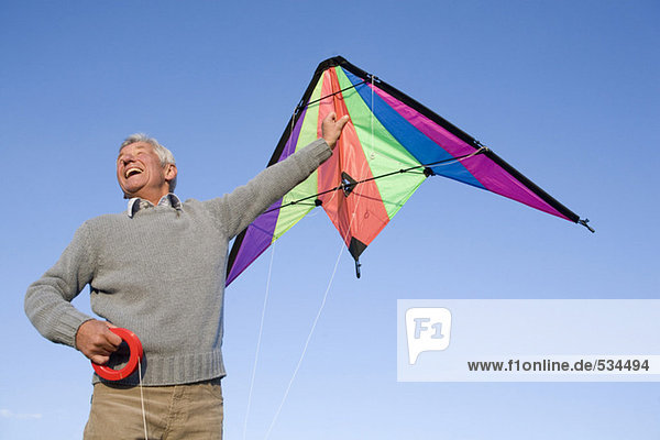 Senior Mann beim Drachenfliegen  lächelnd  flacher Blickwinkel