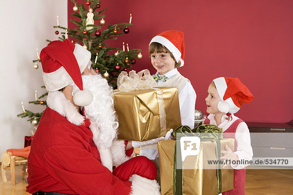 Kinder (3-7) erhalten Geschenke vom Weihnachtsmann  lächelnd