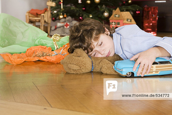 Boy sleeping under Christmas tree  holding toy car