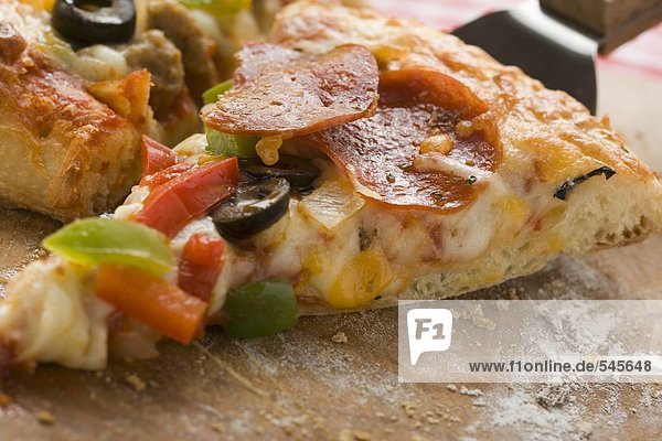Stück Pizza mit Peperoniwurst  Paprika und Oliven auf Heber
