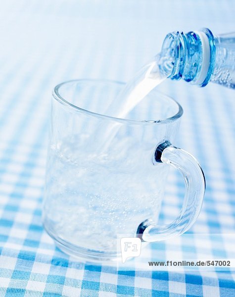 Mineralwasser in ein Glas giessen