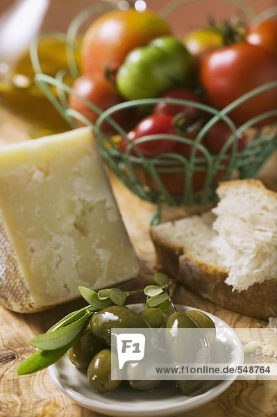 Tomaten im Drahtkorb  Oliven  Käse  Brot und Olivenöl