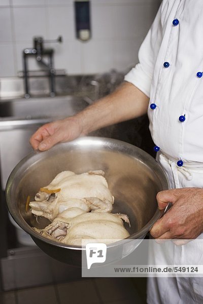 Chef carrying bowl containing two chickens