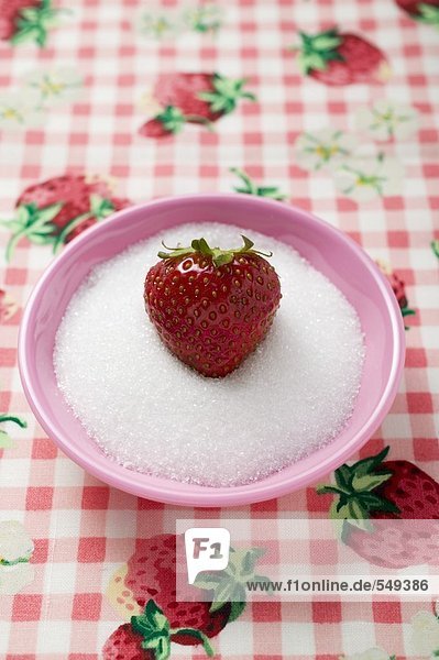 Strawberry in a small dish of sugar