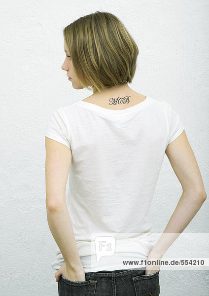 Teenage girl standing with hands in back pockets  rear view  portrait